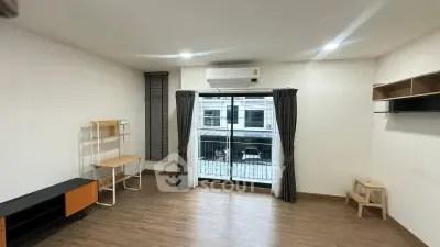 Spacious living room with modern decor and large window offering natural light.