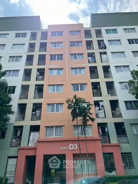 Modern multi-story apartment building with colorful facade and lush greenery.