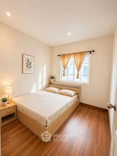 Cozy bedroom with natural light, wooden flooring, and elegant decor