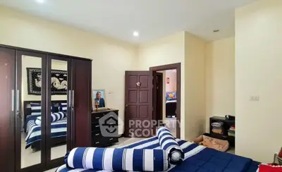 Cozy bedroom with striped bedding and mirrored wardrobe in modern apartment.