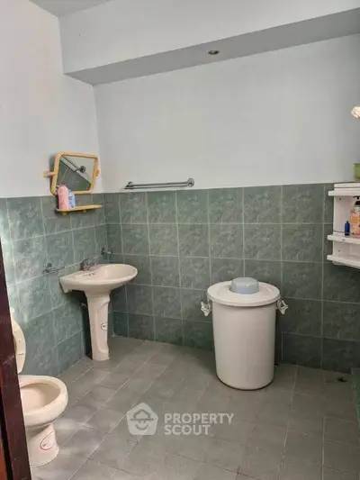 Spacious bathroom with green tiles and essential fixtures, ideal for modern living.