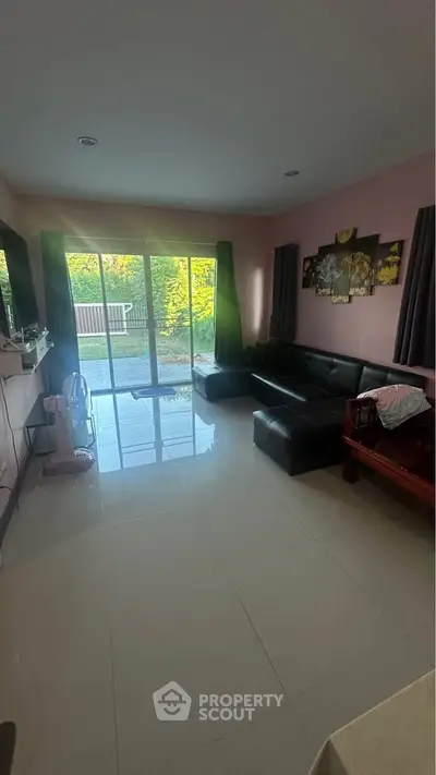 Spacious living room with large glass doors opening to a lush garden view.