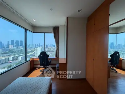 Spacious bedroom with city view, featuring a study desk and large windows for natural light.