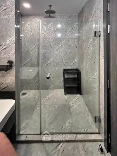 Elegant modern bathroom with glass shower enclosure and marble walls.