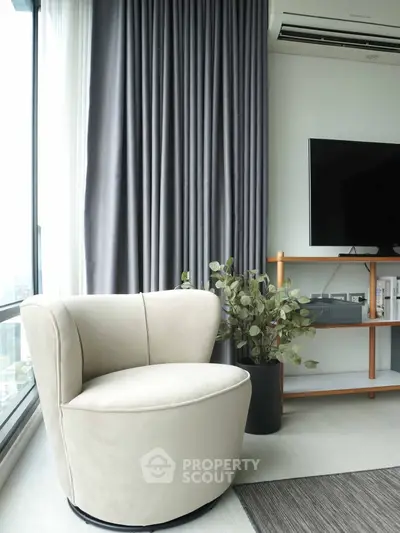 Modern living room with stylish chair, large window, and sleek TV setup.