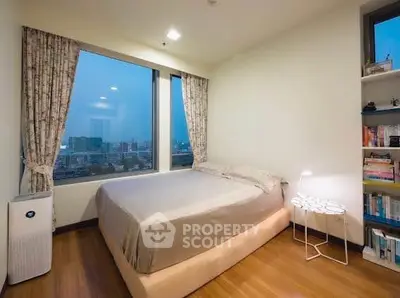 Cozy bedroom with city view, featuring large windows and elegant decor.