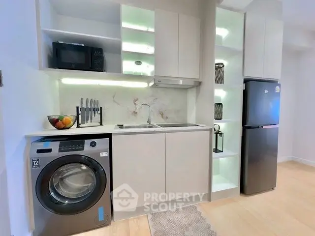 Modern kitchen with sleek appliances and integrated washing machine in stylish apartment.