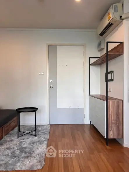 Modern living room with wooden flooring, stylish shelving, and air conditioning unit.