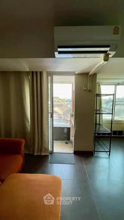 Cozy living room with air conditioning and balcony access, perfect for relaxation.