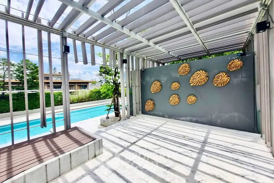 Stunning outdoor pool area with modern pergola and artistic wall decor, perfect for relaxation and entertainment.