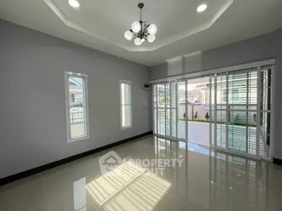 Spacious living room with modern lighting and large windows overlooking a garden.