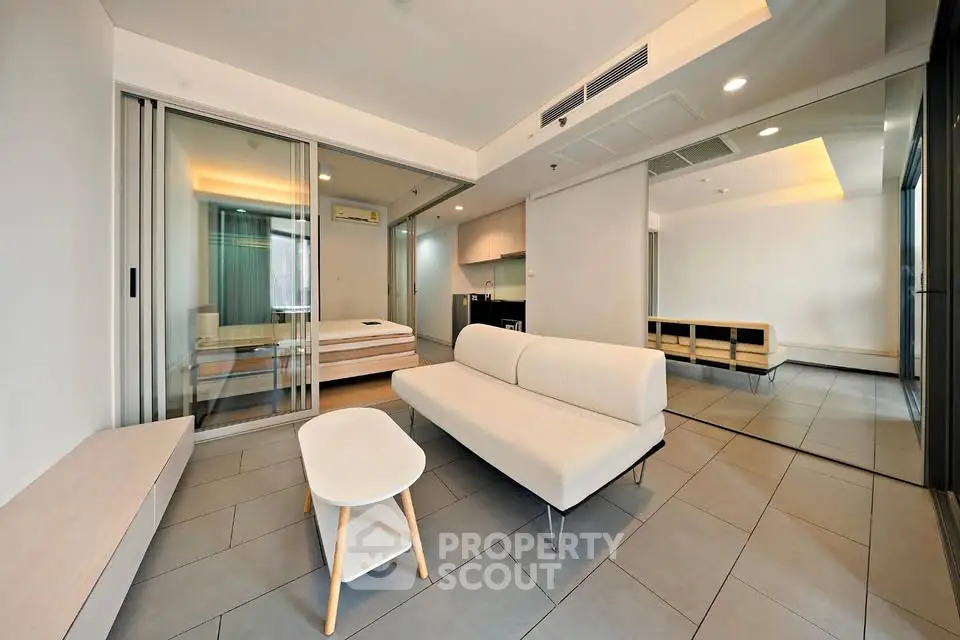 Modern living room with sleek furniture and mirrored wall in a stylish apartment.
