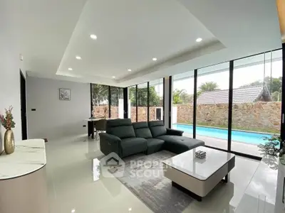 Luxurious modern living room with pool view, sleek furniture, and floor-to-ceiling windows.