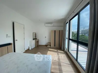 Bright bedroom with large windows and modern furnishings, offering a serene and airy atmosphere.