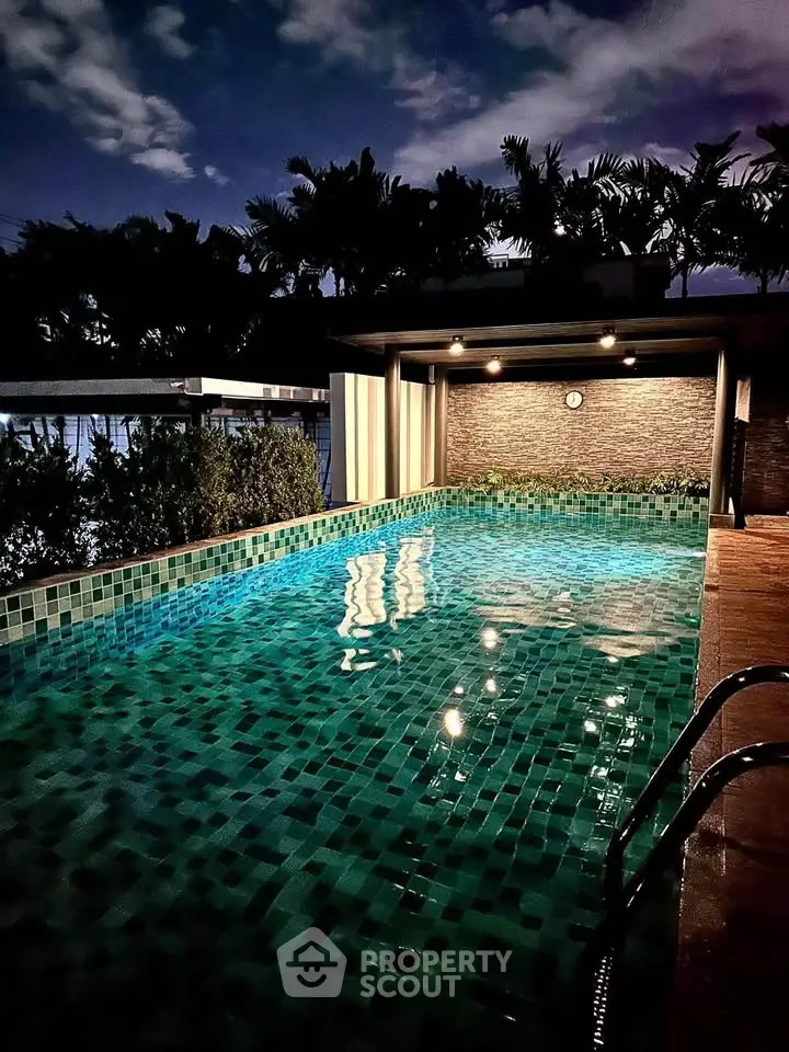 Luxurious rooftop pool with ambient lighting and lush surroundings, perfect for relaxation and entertainment.