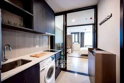 Modern kitchen with washing machine and open layout leading to bedroom