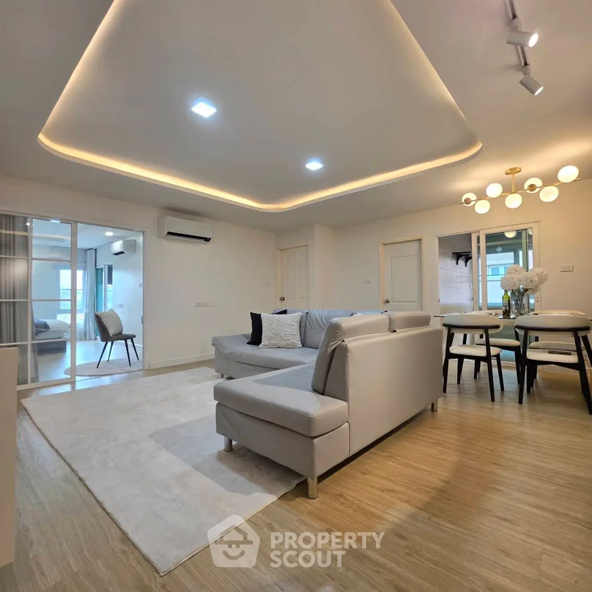 Modern living room with stylish lighting and open layout, featuring a cozy sectional sofa and elegant dining area.