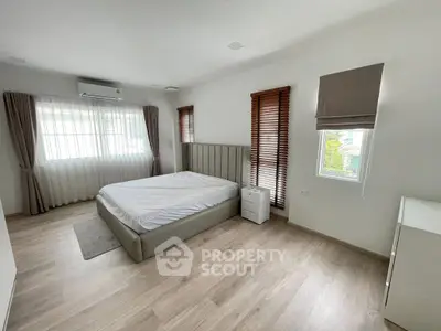 Spacious and bright bedroom with modern decor and large windows.