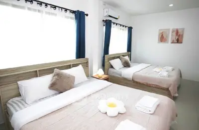 Spacious bedroom with two cozy beds, modern decor, and ample natural light.