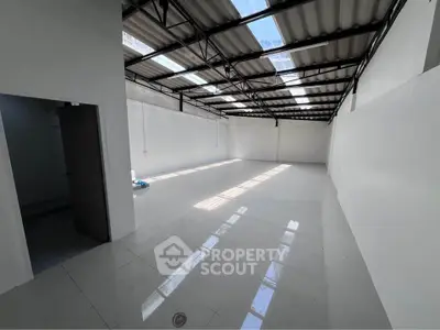 Spacious industrial-style room with high ceilings and natural light, perfect for creative workspace or storage.