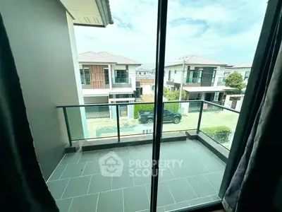 Charming balcony view overlooking modern suburban homes with sleek glass railing.