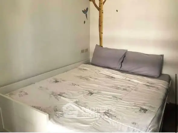 Cozy bedroom with unique tree wall decal and comfortable bedding, perfect for relaxation.