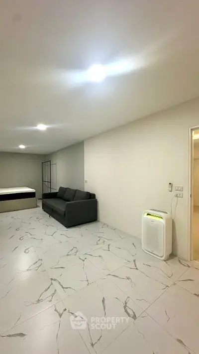 Spacious modern living room with sleek marble flooring and minimalist furniture.