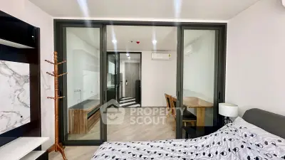 Modern studio apartment with glass partition, stylish furniture, and sleek flooring.