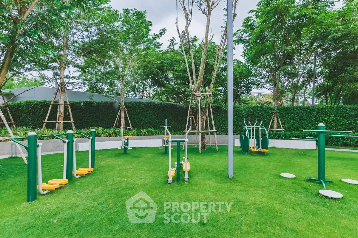 Outdoor gym area in lush green garden with modern exercise equipment.