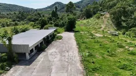 Expansive industrial property with lush green surroundings and mountain views.