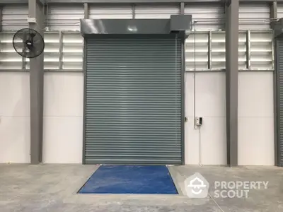 Industrial warehouse with large roller shutter door and concrete flooring