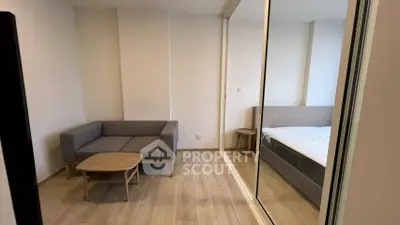 Modern apartment with cozy living area and mirrored sliding doors leading to bedroom.