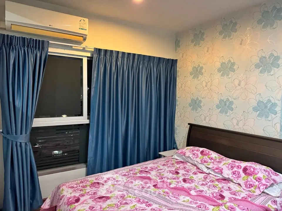 Cozy bedroom with floral wallpaper and air conditioning, featuring a comfortable bed and blue curtains.