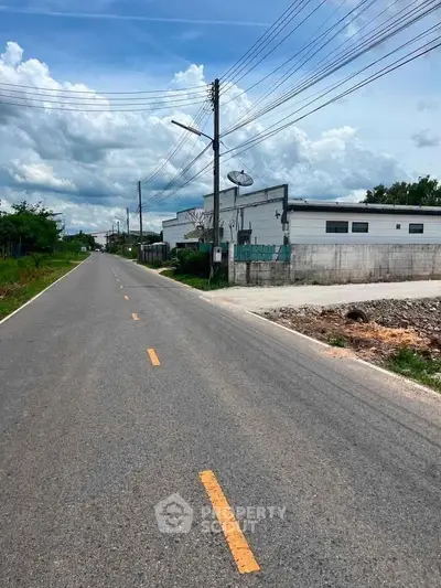 Spacious road view with adjacent industrial building under clear blue sky.