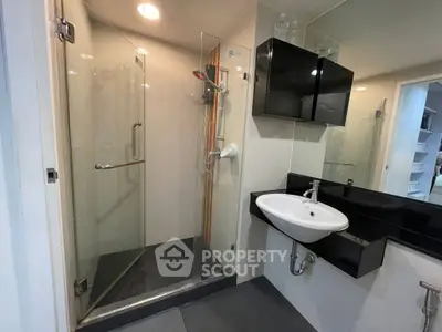 Modern bathroom with sleek shower and stylish sink in contemporary apartment.