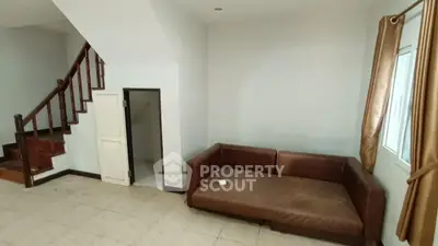 Spacious living room with brown leather sofa and staircase, ideal for modern family living.