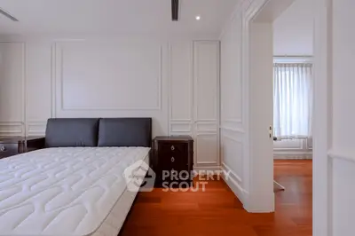 Spacious bedroom with elegant wood flooring and classic paneling