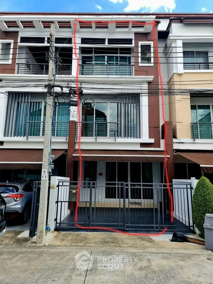 Modern townhouse exterior with gated entrance and large windows in urban setting.