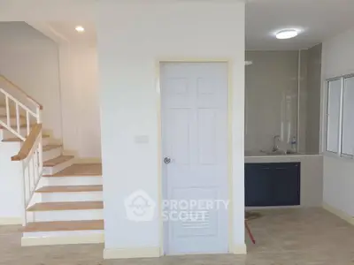 Modern interior with staircase and compact kitchen area in a bright, minimalist home.
