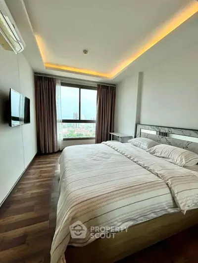 Modern bedroom with city view, featuring elegant lighting and hardwood floors.