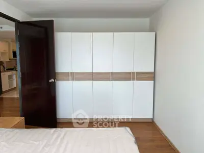 Spacious bedroom with modern wardrobe and wooden flooring, perfect for comfortable living.