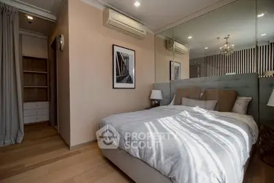 Elegant bedroom with mirrored wall and modern decor in a cozy apartment.