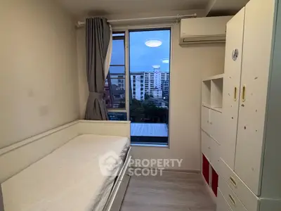 Cozy bedroom with single bed and city view, featuring ample storage and modern design.