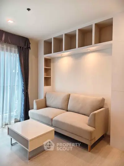 Modern living room with cozy beige sofa and sleek coffee table, featuring built-in shelving and natural light.