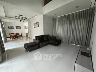 Spacious modern living room with sleek furniture and dining area, perfect for entertaining.