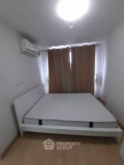 Cozy bedroom with minimalist design featuring a comfortable bed and air conditioning, perfect for restful nights.