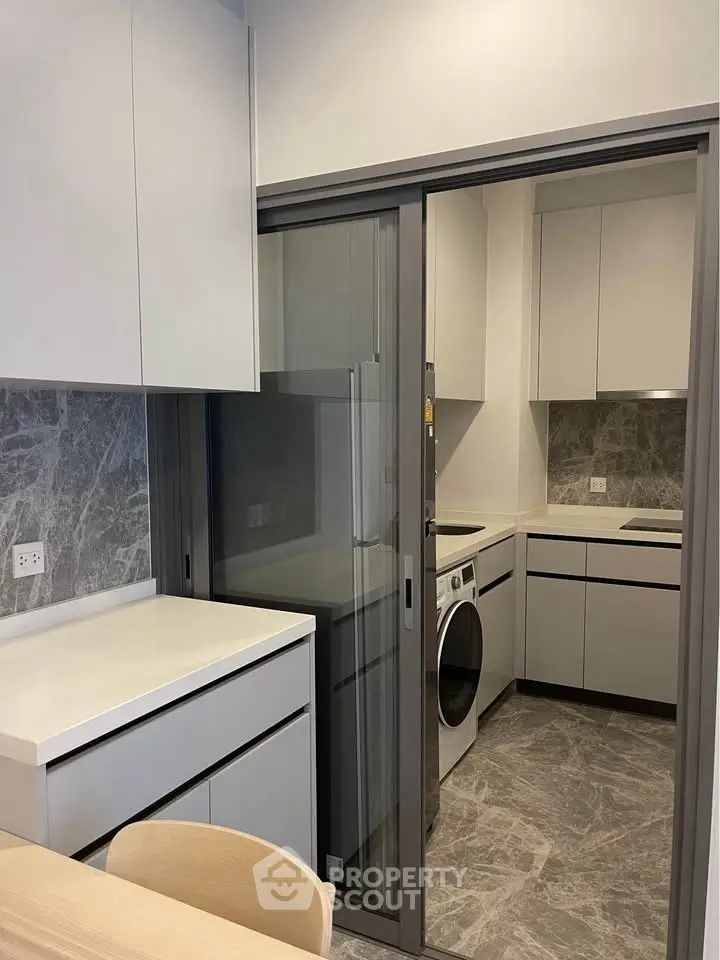 Modern kitchen with sleek cabinetry and integrated washing machine in compact layout.