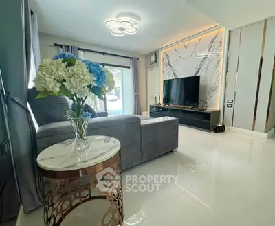 Luxurious living room with modern decor, plush sofa, and large TV, perfect for relaxation and entertainment.