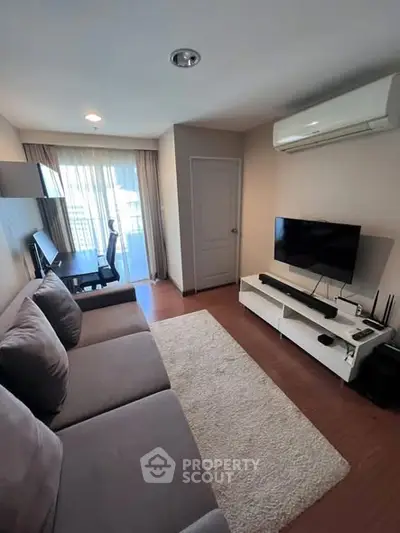 Modern living room with cozy sofa, TV, and natural light from large window.
