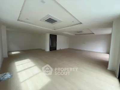Spacious empty room with modern ceiling design and wooden flooring, ideal for customization.